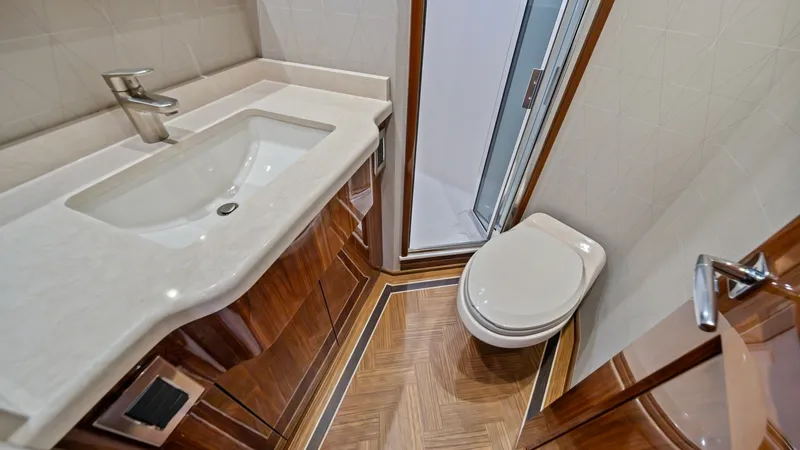 Slide: The Image of Elegant En-Suite Bathroom This en-suite bathroom on the 2021 Viking 72 Enclosed Bridge features a sophisticated design with polished wooden cabinetry and a sleek, integrated sink. The space is accentuated by intricate wood flooring and a well-appointed shower. Modern fixtures and - 7377920