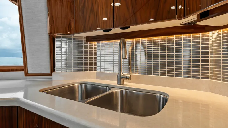 Slide: The Image of Galley with Modern Fixtures The 2021 Viking 72 Enclosed Bridge galley features high-gloss wood cabinetry and a sleek, dual-basin stainless steel sink. The contemporary backsplash and under-cabinet lighting enhance the luxurious feel, while the expansive counter space provides ample - 7377896