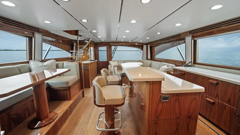 Slide: The Image of Spacious Interior Salon with Ocean Views This luxurious interior salon of the 2021 Viking 72 Enclosed Bridge features elegant wood finishes and plush seating arrangements. Expansive windows provide breathtaking ocean views, while recessed lighting enhances the sophisticated ambiance. The open la - 7377902