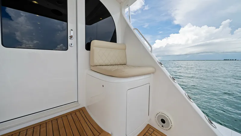 Slide: The Image of Aft Deck Seating Area This image showcases the elegant aft deck seating area on the Viking 72 Enclosed Bridge. The teak flooring complements the plush, cushioned seat with its sleek design, offering both comfort and style. The view from this vantage point provides a serene bac - 7377937