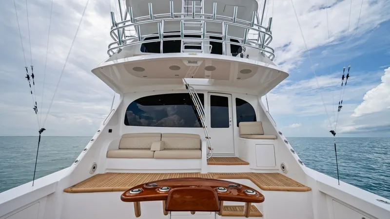 Slide: The Image of Aft Deck with Fishing Station This image showcases the aft deck of the 2021 Viking 72 Enclosed Bridge, featuring a well-equipped fishing station with a polished wood table. The spacious area includes comfortable seating, ideal for relaxation while enjoying open ocean views. The deck's - 7377876