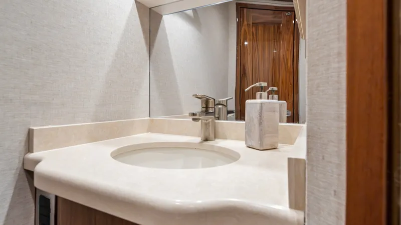 Slide: The Image of Elegant Vanity in Enclosed Head This image showcases the elegant vanity area within the enclosed head of the 2021 Viking 72 Enclosed Bridge. The sleek countertop features a modern, integrated sink and high-end fixtures, exuding luxury and sophistication. The warm wood accents and soft l - 7377926