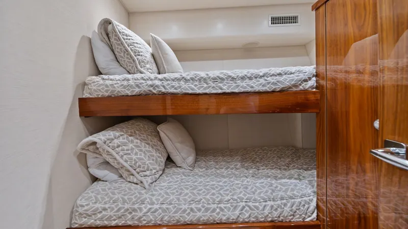 Slide: The Image of Guest Cabin with Bunk Beds This cozy guest cabin features well-appointed bunk beds, providing comfortable sleeping arrangements for additional guests. The space is elegantly designed with warm wood finishes and soft, patterned bedding, creating a welcoming atmosphere. Overhead ligh - 7377913