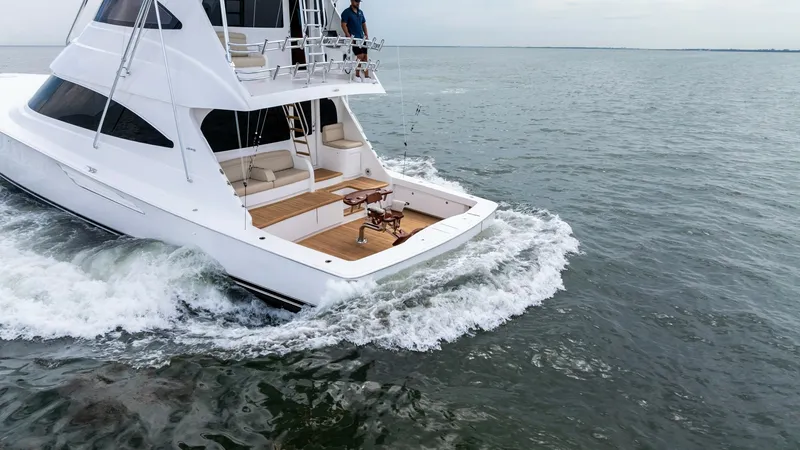 Slide: The Image of Aft Deck and Upper Helm View This image showcases the aft deck of the 2021 Viking 72 Enclosed Bridge, featuring a spacious teak deck for leisure and fishing activities. The upper helm provides an elevated vantage point for navigation, enhancing visibility and control. The sleek, mode - 7377962