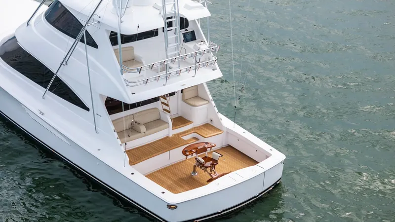 Slide: The Image of Aft Deck with Fishing Chair This image showcases the aft deck of the 2021 Viking 72 Enclosed Bridge, featuring a spacious and well-equipped fishing area. The teak decking provides a luxurious touch, complemented by the robust fighting chair positioned at the center for optimal angli - 7377961