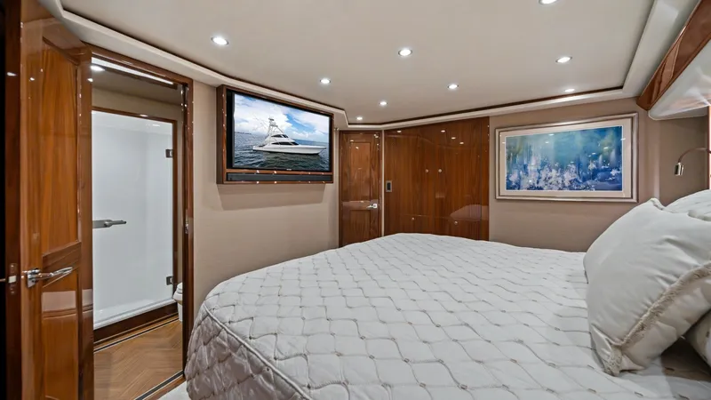 Slide: The Image of Luxurious Master Stateroom This elegant master stateroom features a plush queen-size bed with a finely quilted bedspread, surrounded by warm wood paneling. The room is beautifully illuminated with recessed lighting, complemented by a large flat-screen TV and stylish artwork. The en - 7377907