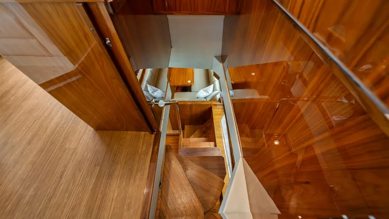 Slide: The Image of Stairway to Lower Deck Interior This image showcases the elegant stairway leading to the lower deck of the Viking 72 Enclosed Bridge. The polished wood paneling and sleek handrails enhance the luxurious feel of the vessel, reflecting fine craftsmanship. Soft ambient lighting complements - 7377888