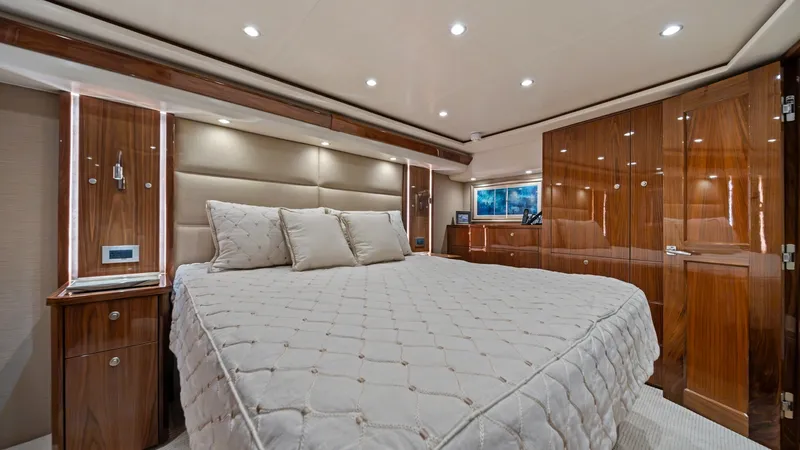 Slide: The Image of Luxurious Master Stateroom Interior This master stateroom exudes elegance and comfort, featuring a plush, king-sized bed with a stylish quilted cover. The rich wood cabinetry and paneling, paired with soft ambient lighting, create a warm and inviting atmosphere. Ample storage and a sleek, b - 7377905