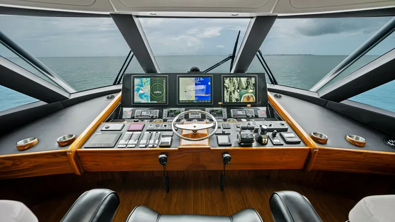 Slide: The Image of Command Helm with Panoramic Views The enclosed bridge of the 2021 Viking 72 features a state-of-the-art command helm, equipped with advanced navigation displays and controls. Rich wood finishes and sleek black leather seating provide a luxurious and functional environment for captaining. - 7377874