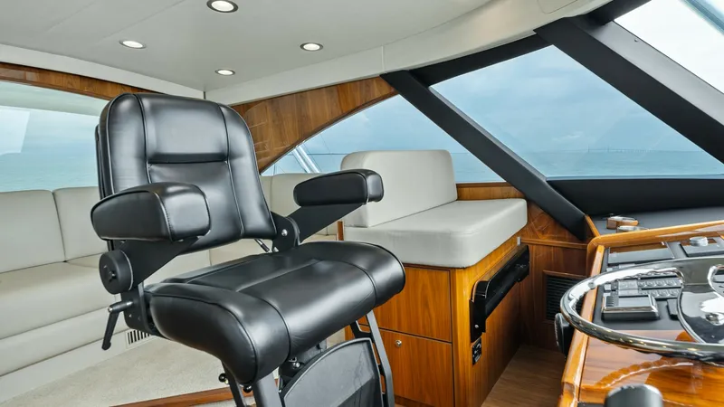 Slide: The Image of Helm Station with Captain's Chair This helm station of the 2021 Viking 72 Enclosed Bridge features a luxurious captain's chair upholstered in premium black leather, offering comfort and support for long voyages. The area is enhanced by rich wooden finishes and sleek, modern instrumentatio - 7377884