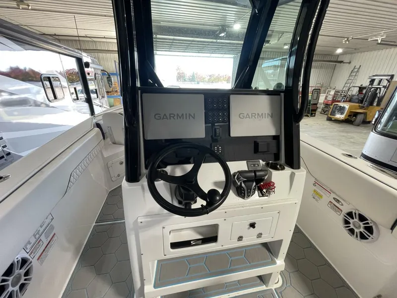 Slide: The Image of Dual Garmin Helm Electronics and Steering Console Setup Modern center console helm with dual Garmin displays, stainless wheel, switch panel, and throttle controls. Clean and advanced marine electronics setup. - 5799733