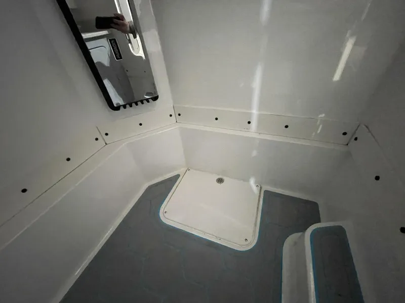 Slide: The Image of Shower Pan and Fiberglass Interior in Boat Head Compartment Head compartment featuring shower drain, fiberglass wall panels, and mirror. Low-maintenance, easy-clean marine bathroom design. - 5799729