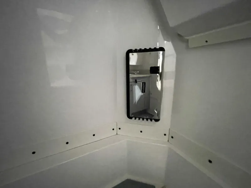 Slide: The Image of Mounted Mirror Inside Center Console Boat Head Interior shot of the boat’s head compartment showing a large mounted mirror and surrounding fiberglass finish. Clean and convenient onboard restroom setup. - 5799730