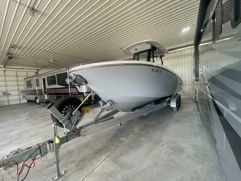 Slide: The Image of Front View of Stingray Center Console Boat in Storage Facility Crisp front-angle shot of a Stingray center console boat on a Yacht Club trailer, highlighting its deep-V hull design and protected indoor storage environment. - 5799747