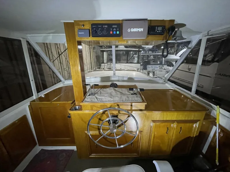 Slide: The Image of Upper Helm with Wood Console and Garmin Electronics – Egg Harbor 40 Clean upper helm station featuring wood cabinetry, large wheel, and Garmin electronics with excellent visibility forward. - 5808861