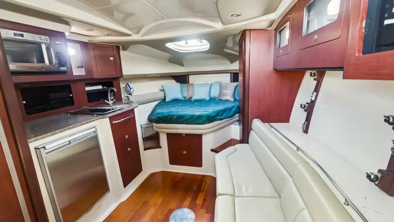 Slide: The Image of Interior Cabin with Galley and Berth The interior cabin of the 2008 Boston Whaler 34 Outrage features a cozy berth with plush bedding and a skylight for natural light. The adjacent galley is equipped with modern appliances and rich wood cabinetry, offering a blend of functionality and style. - 7672493