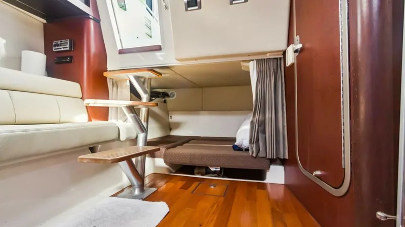 Slide: The Image of Cabin Interior with Sleeping Area This inviting cabin interior of the 2008 Boston Whaler 34 Outrage features rich wooden flooring and elegant finishes. The space includes a comfortable sleeping area with privacy curtains, perfect for overnight stays. The seating area and practical storage - 7672498