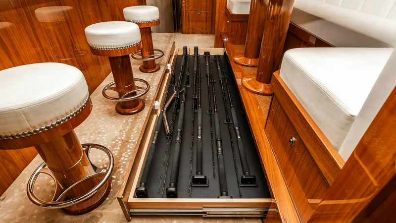 Slide: The Image of Salon with Integrated Rod Storage The 2019 Viking 80 Skybridge features a luxurious salon with beautifully crafted wood finishes and plush seating. A standout feature is the innovative, built-in floor storage for fishing rods, maximizing space and functionality. The elegant bar stools and - 6613320