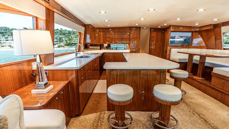 Slide: The Image of Spacious Galley and Dining Area The galley of the 2019 Viking 80 Skybridge exudes elegance with its high-gloss wood cabinetry and expansive countertops. Natural light floods the area through large windows, complementing the modern fixtures and ample storage. Adjacent to the galley, the - 6478708