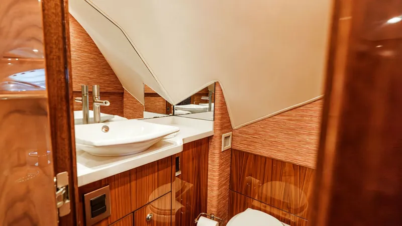 Slide: The Image of Elegant Day Head This stylish guest bathroom on the Viking 80 Skybridge features luxurious wood finishes and contemporary fixtures. The vessel sink and modern faucet complement the sleek design, while the ample lighting creates a warm and inviting atmosphere. The space is - 6478713