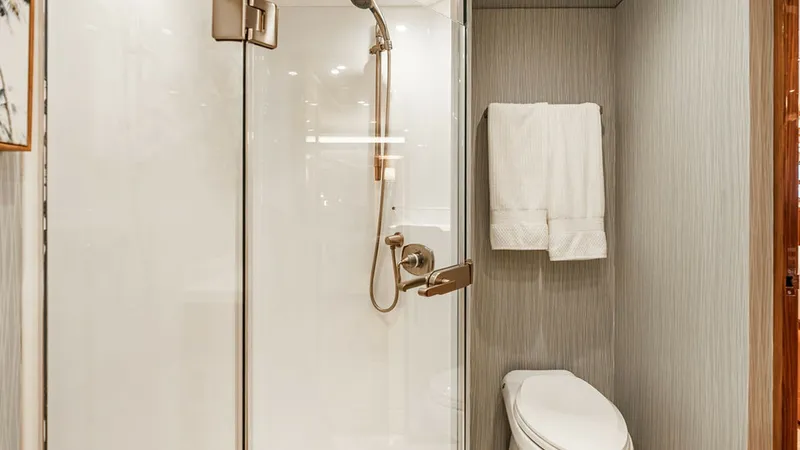 Slide: The Image of Luxurious Master Head This elegant ensuite bathroom features a spacious glass-enclosed shower with modern fixtures and a sleek, high-gloss finish. The room is complemented by sophisticated wall textures and warm wood accents, creating a serene and upscale ambiance. High-qualit - 6478722