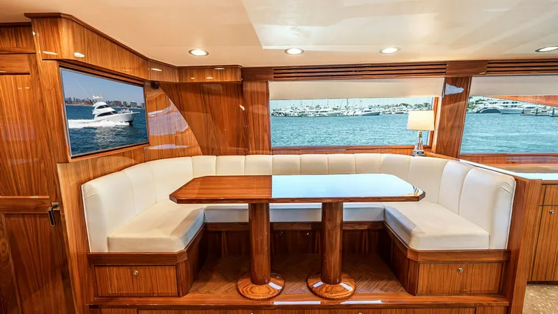 Slide: The Image of Elegant Salon Dining Area This inviting salon dining area on the 2019 Viking 80 Skybridge features a beautifully crafted wooden table surrounded by plush, white upholstered seating. The large windows provide stunning views of the surrounding seascape, creating a perfect ambiance f - 6478712
