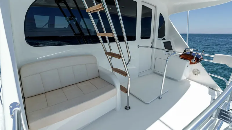 Slide: The Image of Skybridge Seating and Helm Access This image showcases the skybridge seating area of the 2019 Viking 80 Skybridge. A plush, built-in bench offers comfortable seating with easy access to the helm. The sleek stainless steel ladder leads to the upper helm, emphasizing the yacht's modern desi - 6478746