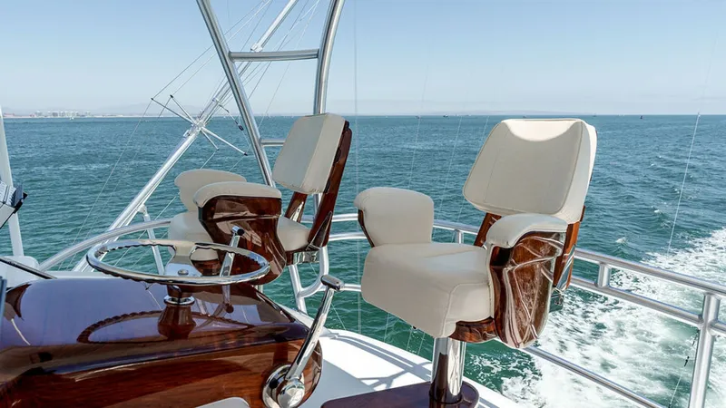 Slide: The Image of Skybridge Helm Seating Area Experience luxury and control from the skybridge of the 2019 Viking 80 Skybridge. This area features plush, ergonomically designed helm chairs with rich wood accents, providing comfort and style. The panoramic views and sleek helm station ensure an unpara - 6478748
