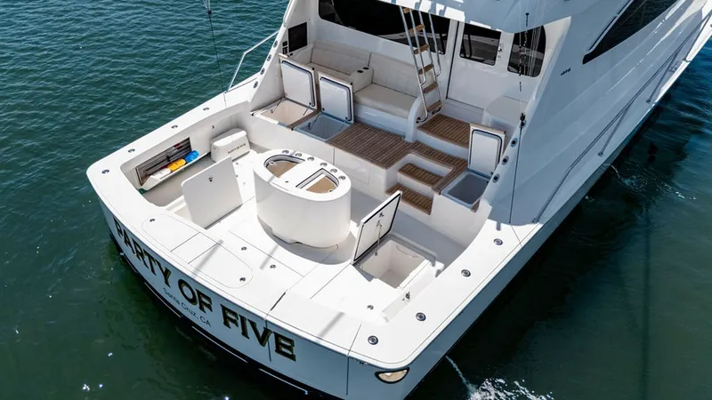 Slide: The Image of Spacious Aft Deck with Seating Area The aft deck of the 2019 Viking 80 Skybridge, 'PARTY OF FIVE', features a spacious layout ideal for leisure and entertainment. The area includes comfortable seating with ample storage, complemented by a central circular bait station, perfect for fishing e - 6478767