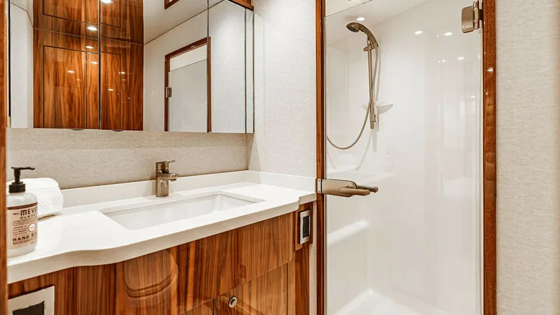 Slide: The Image of Luxurious Ensuite Bathroom This elegant ensuite bathroom features high-gloss wood cabinetry and sleek white countertops, offering a sophisticated and modern aesthetic. The spacious shower area includes a premium fixture, adding to the luxurious feel. Ample mirror space and soft lig - 6478725