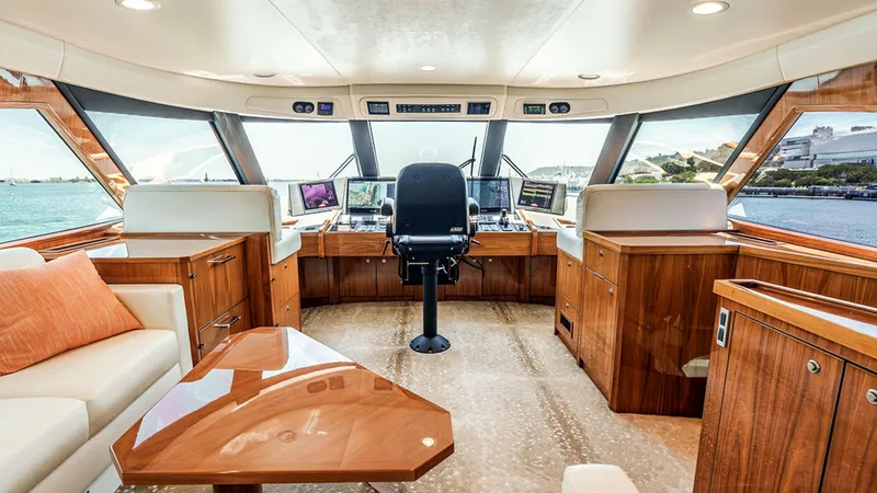 Slide: The Image of Skybridge Helm with Panoramic Views This elegant skybridge helm of the 2019 Viking 80 showcases state-of-the-art navigation equipment surrounded by expansive windows for panoramic views. The polished wood cabinetry and plush seating provide a luxurious and functional command center. Soft am - 6478739