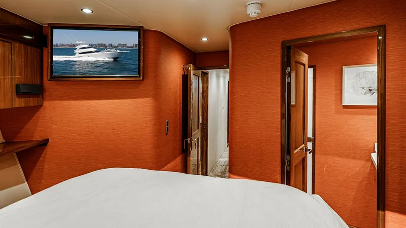 Slide: The Image of Guest Stateroom with Ensuite This inviting guest stateroom features a comfortable bed, accented by warm, rich wall textures that create a cozy atmosphere. A flat-screen TV is mounted for entertainment, while recessed lighting adds a modern touch. The ensuite bathroom offers convenien - 6478733