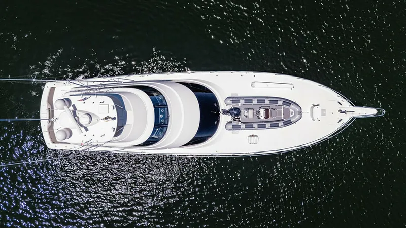 Slide: The Image of Aerial View of Yacht Decks This aerial image showcases the sleek design of the Viking 80 Skybridge, PARTY OF FIVE. The spacious decks are elegantly arranged, featuring a well-appointed skybridge and a luxurious foredeck sunpad area. The yacht's streamlined profile and pristine whit - 6478779