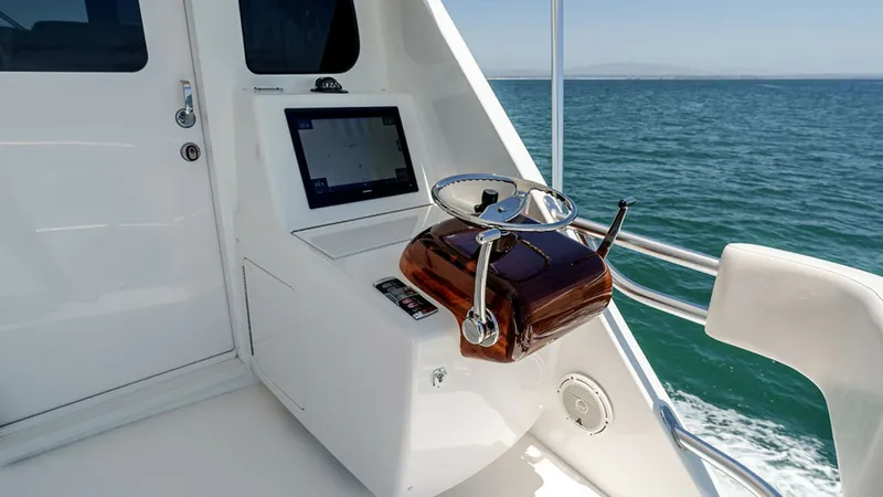 Slide: The Image of Skybridge Helm Station The helm station on the Viking 80 Skybridge offers a commanding view, equipped with state-of-the-art navigation technology. The polished wooden steering wheel and sleek console design highlight the vessel's luxurious craftsmanship. Expansive ocean views p - 6478745