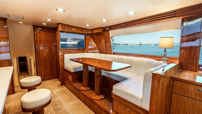 Slide: The Image of Elegant Salon Dining Area This inviting salon on the 2019 Viking 80 Skybridge features a sophisticated dining area with plush, wrap-around seating and a polished wood table. The rich wood finishes and ambient lighting provide a warm and luxurious atmosphere. Large windows offer st - 6478711