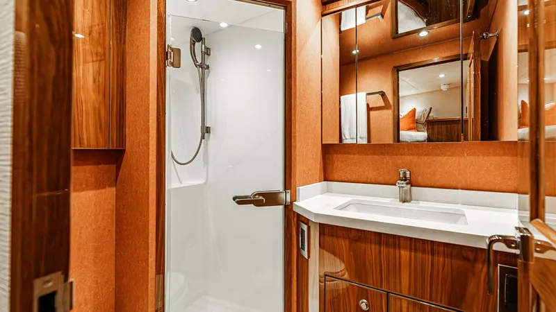 Slide: The Image of Luxurious Ensuite Bathroom This elegant ensuite bathroom on the 2019 Viking 80 Skybridge features a sleek, modern design with high-quality finishes. The spacious shower is enclosed in glass, complemented by a stylish vanity with a polished countertop and ample storage. Warm wood ac - 6478728