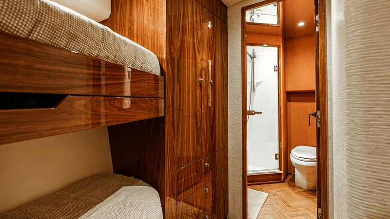 Slide: The Image of Guest Cabin with Ensuite Bathroom This inviting guest cabin on the 2019 Viking 80 Skybridge features warm wood finishes and comfortable bunk accommodations. The space is thoughtfully designed with ample storage and direct access to a private ensuite bathroom. Elegant fixtures and modern a - 6478729