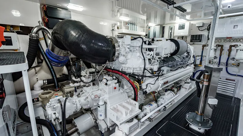 Slide: The Image of Engine Room with Twin Engines The engine room of the 2019 Viking 80 Skybridge, 'PARTY OF FIVE,' showcases its powerful twin engines. The space is meticulously organized, with sleek white finishes and high-quality materials providing a clean and efficient environment. The advanced engi - 6478753