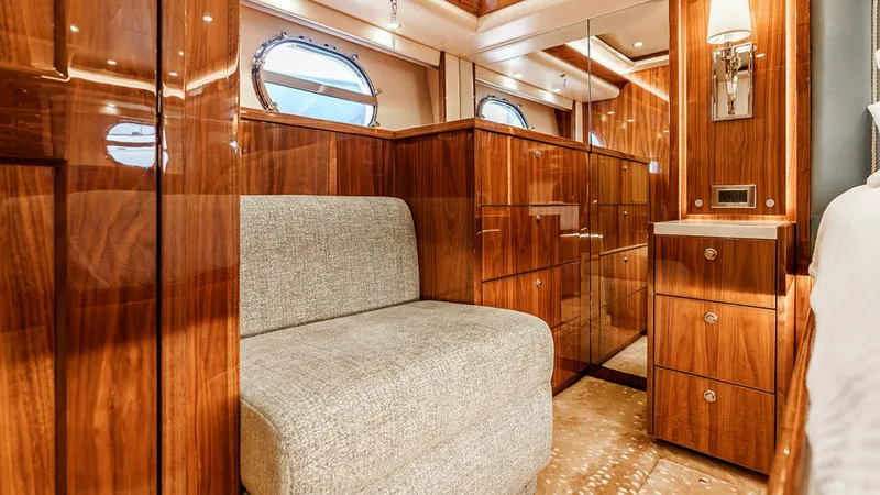 Slide: The Image of Luxurious Guest Stateroom Interior This guest stateroom exudes elegance with its high-gloss wood finishes and plush seating area. The space is thoughtfully designed with ample storage, mirrored cabinetry, and ambient lighting that enhances the warm tones of the room. Large porthole windows - 6478718