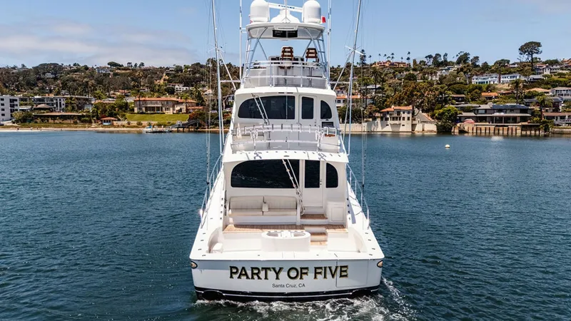Slide: The Image of Aft View with Skybridge This image showcases the sleek and impressive aft view of the 2019 Viking 80 Skybridge, 'PARTY OF FIVE'. The vessel's spacious cockpit is designed for both leisure and sportfishing, featuring a teak deck and elegant seating. The skybridge above offers a c - 6478780