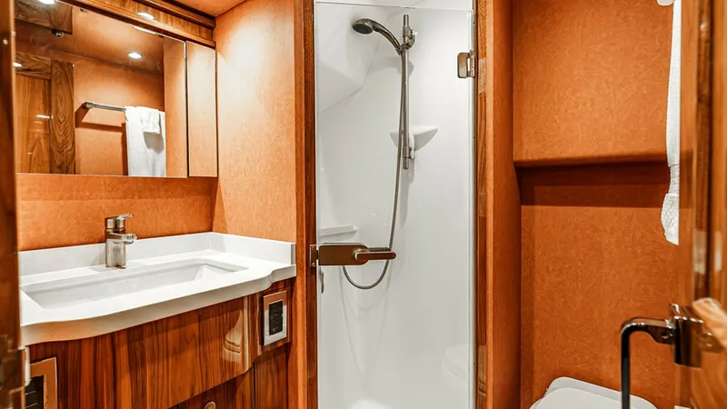 Slide: The Image of Luxurious Guest Ensuite Bathroom This elegant ensuite bathroom on the Viking 80 Skybridge offers a sophisticated design with warm wood cabinetry and soft overhead lighting. The space features a modern glass-enclosed shower and a sleek vanity with ample storage. The refined finishes and t - 6478731