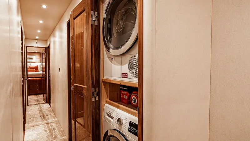 Slide: The Image of Hallway with Laundry Facilities This image showcases a hallway on the 2019 Viking 80 Skybridge, featuring built-in laundry facilities. The stacked washer and dryer are conveniently tucked into a dedicated space, maximizing functionality without compromising on style. The hallway is eleg - 6478737
