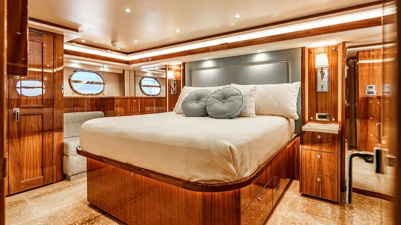 Slide: The Image of Luxurious Master Stateroom This elegant master stateroom aboard the 2019 Viking 80 Skybridge exudes luxury with its rich wood finishes and plush bedding. The room features ample natural light from the round portholes, creating a warm and inviting atmosphere. Modern conveniences inc - 6478704