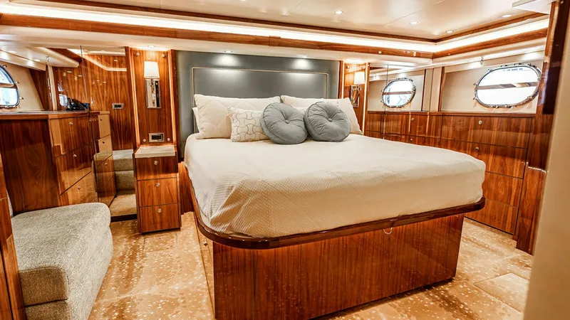 Slide: The Image of Luxurious Master Stateroom The master stateroom of the Viking 80 Skybridge exudes elegance and comfort with its rich wood finishes and plush bedding. Large windows allow natural light to illuminate the space, enhancing the warm ambiance. The room features ample storage, modern ligh - 6478715