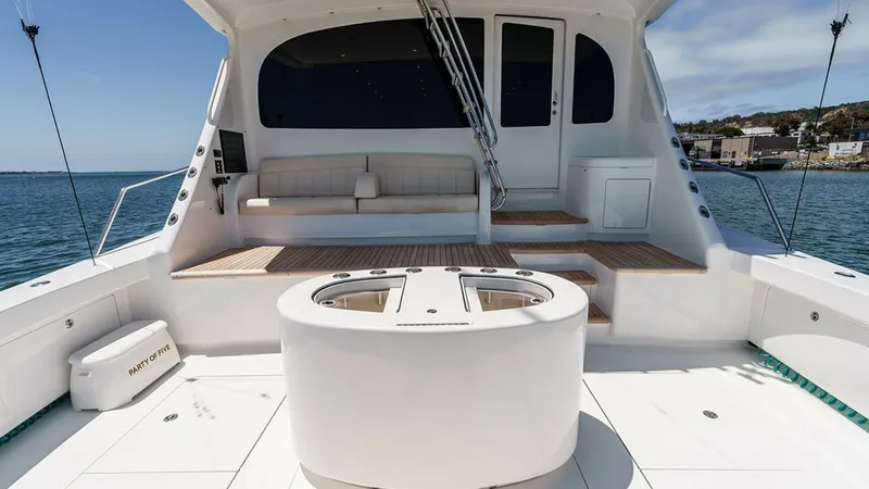 Slide: The Image of Spacious Aft Deck with Seating The aft deck of the 2019 Viking 80 Skybridge offers a generous open space perfect for entertaining. It features a stylish built-in bench with plush cushions, complemented by a sleek, modern design. The area is highlighted by a central circular console, pr - 6478765