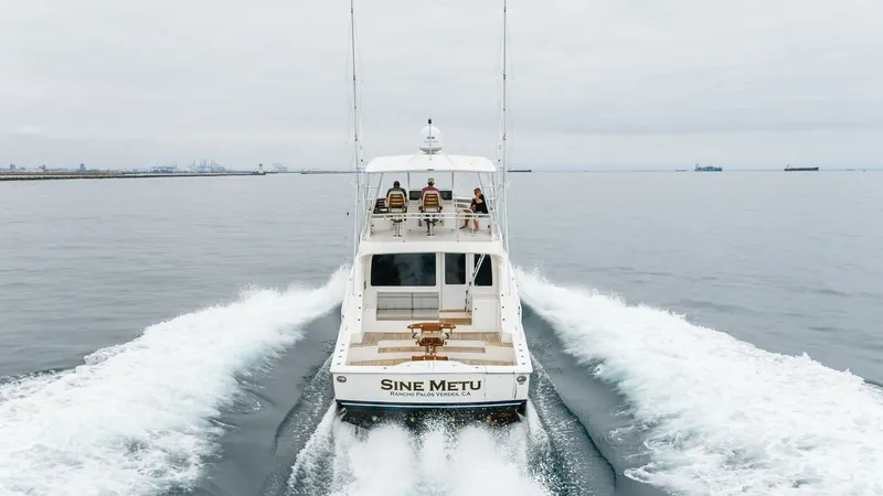 Slide: The Image of Aft View with Fishing Deck The 2020 Bertram 61 Convertible, SINE METU, showcases its expansive aft deck designed for serious fishing enthusiasts. The cockpit is equipped with professional-grade fishing chairs and rod holders, set against a backdrop of open water. The vessel's sleek - 8672996