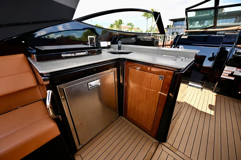 Slide: The Image of Cockpit Wet Bar and Galley, Cruisers Yachts 38 GLS The cockpit wet bar is positioned to support entertaining, featuring a solid surface countertop, stainless steel sink, and built-in refrigeration. The layout provides convenient access from both the helm and seating areas, allowing for efficient service w - 6003075