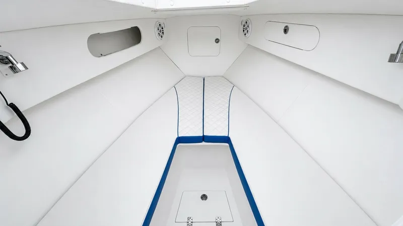 Slide: The Image of Forward Cuddy Cabin Interior This image showcases the forward cuddy cabin of the 2016 Midnight Express 39S Cuddy. The cabin features crisp white upholstery with blue accent piping, creating a modern and inviting space. Overhead speakers and ample storage compartments add to the pract - 6311147