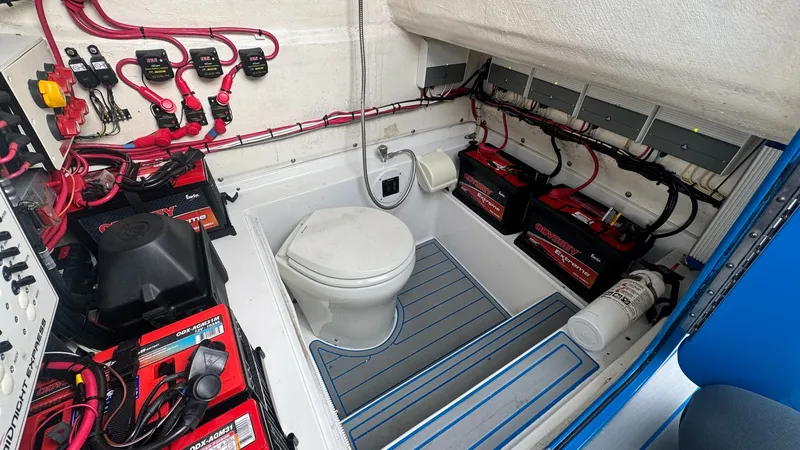 Slide: The Image of Engine Room with Marine Head This image showcases the compact yet functional engine room of the 2016 Midnight Express 39S Cuddy, featuring a marine head for convenience. The space is equipped with organized electrical components and battery systems, ensuring optimal performance and r - 6311151