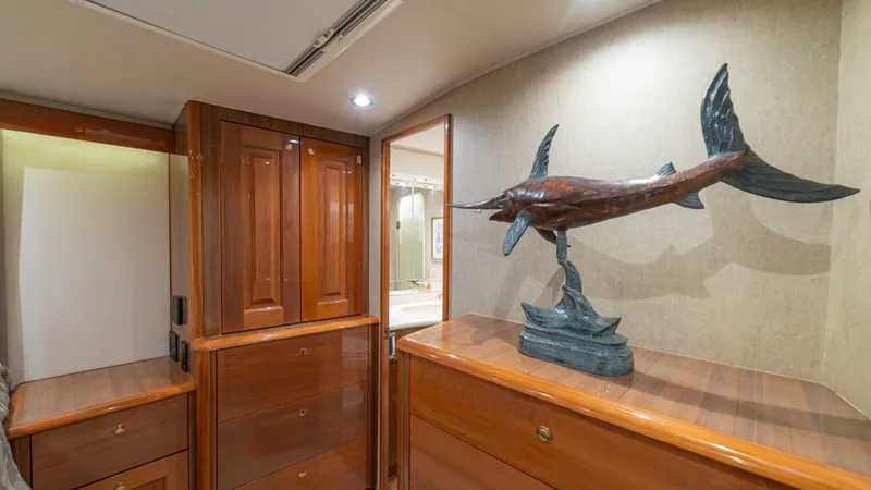 Slide: The Image of Guest Stateroom with Cabinetry This guest stateroom on the 2005 Viking 61 Convertible features elegant wooden cabinetry, providing ample storage space and a warm, inviting atmosphere. The decorative marlin sculpture adds a nautical charm, enhancing the room's character. Soft recessed l - 6449538